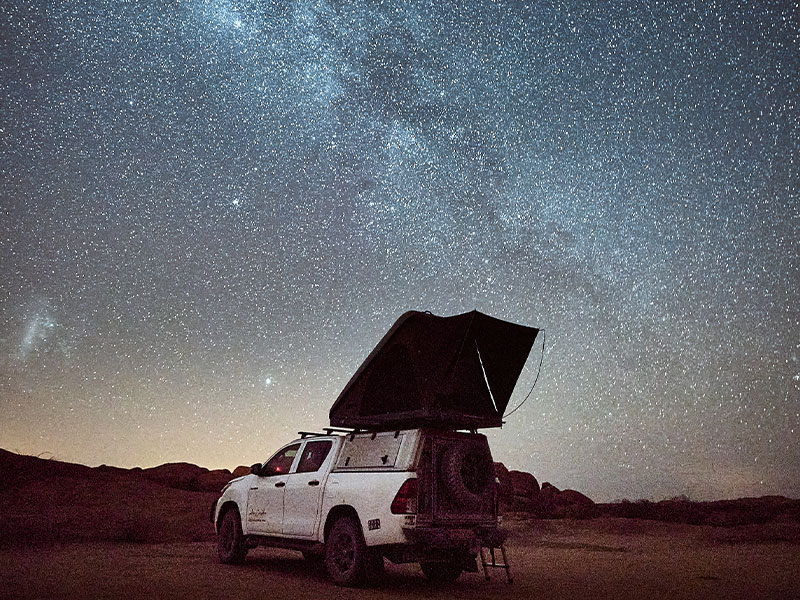 Asco 4x4-huurauto met kampeeruitrusting in Namibi&euml; om te kamperen onder de donkere sterrenhemel en de Melkweg op een afgelegen camping