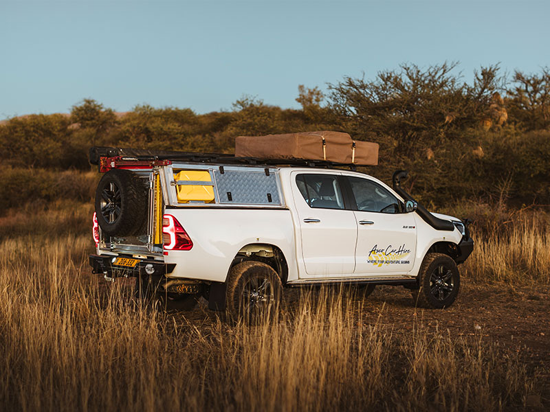 Asco 4x4-huurvoertuig voor 12 personen, geparkeerd op een camping in het Namibische landschap