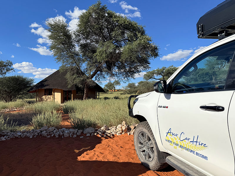 4x4 Asco Car Hire Vehicle parked in Namibian Landscape and a thatched hut