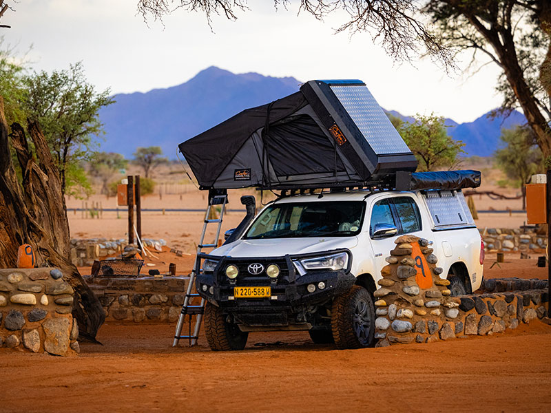Asco 4x4-Mietfahrzeug f&uuml;r Selbstfahrer beim Camping in Sesriem mit ge&ouml;ffnetem Dachzelt