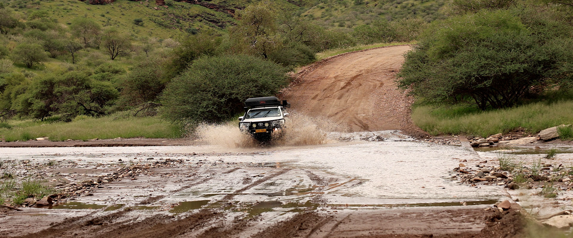 Asco Car Hire 4x4-Mietfahrzeug, das abseits befestigter Stra&szlig;en durch ein Flussbett in Namibia f&auml;hrt.
