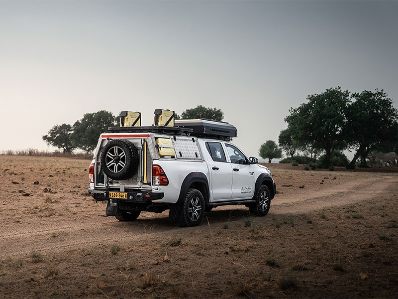 Asco Autohuur Toyota Hilux 4x4-huurauto met twee daktenten, rijdend door het Namibische landschap