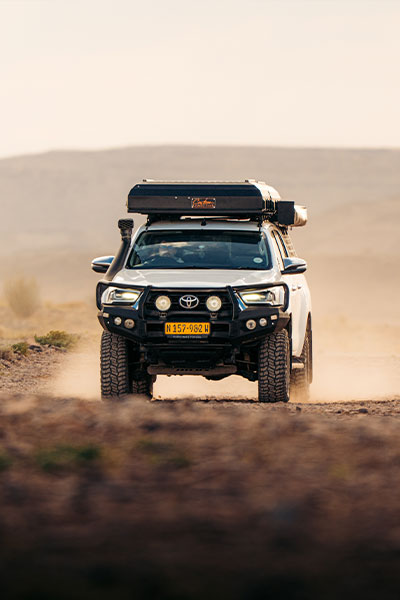 Asco Toyota Hilux Safari 4x4 mit Dachzelt auf einer Schotterstra&szlig;e durch die namibische W&uuml;stenlandschaft