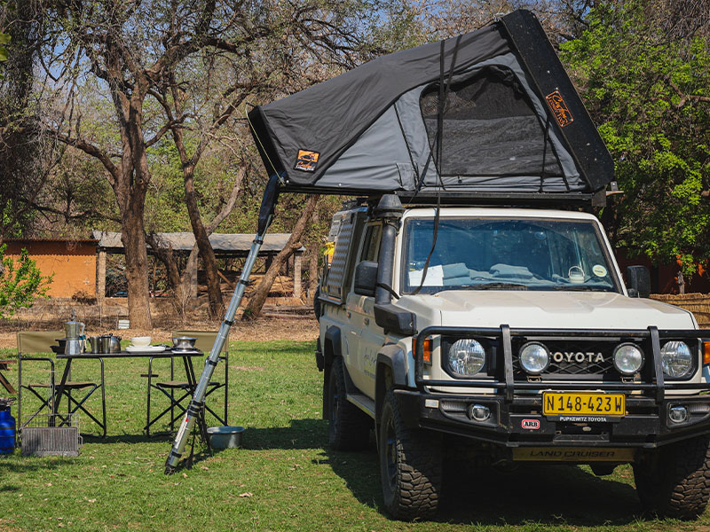 Safari-Campingplatz in Namibia mit einem Asco 4x4-Gel&auml;ndewagen und ge&ouml;ffnetem Dachzelt