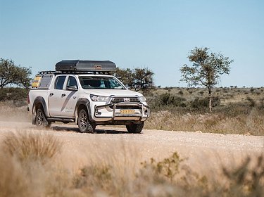 Mietwagen f&uuml;r eine Selbstfahrerreise auf einer staubigen Stra&szlig;e in Namibia, mit geschlossenem Dachzelt